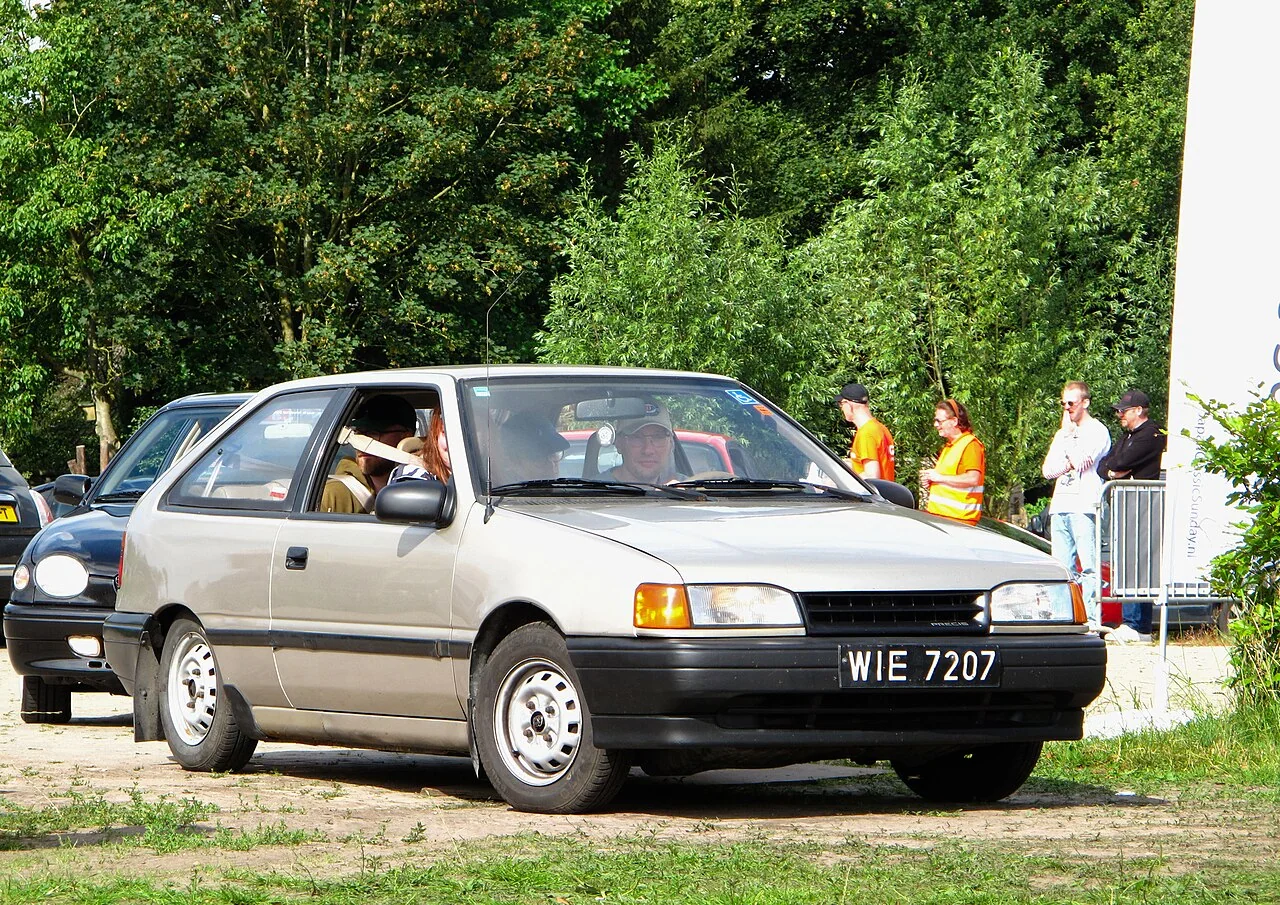 1990–1991 Mitsubishi Precis — representative vehicle generation; Later US-market hatchback body photographed at a 2024 show; exact model year unspecified