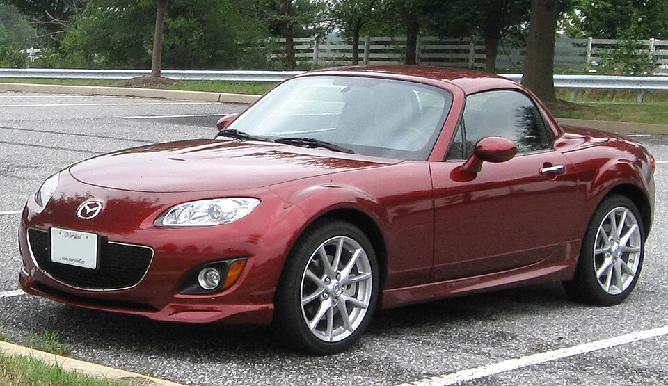 2009–2012 Mazda MX-5 Miata — representative vehicle generation; First North American NC bumper and grille facelift; US 2009 retractable hardtop shown